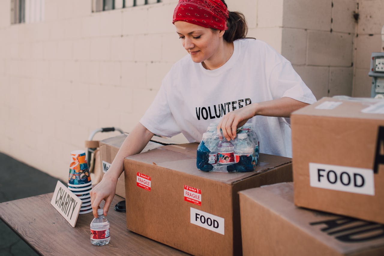 our-experience Woman volunteer sorting food and water for charity distribution at aid center.